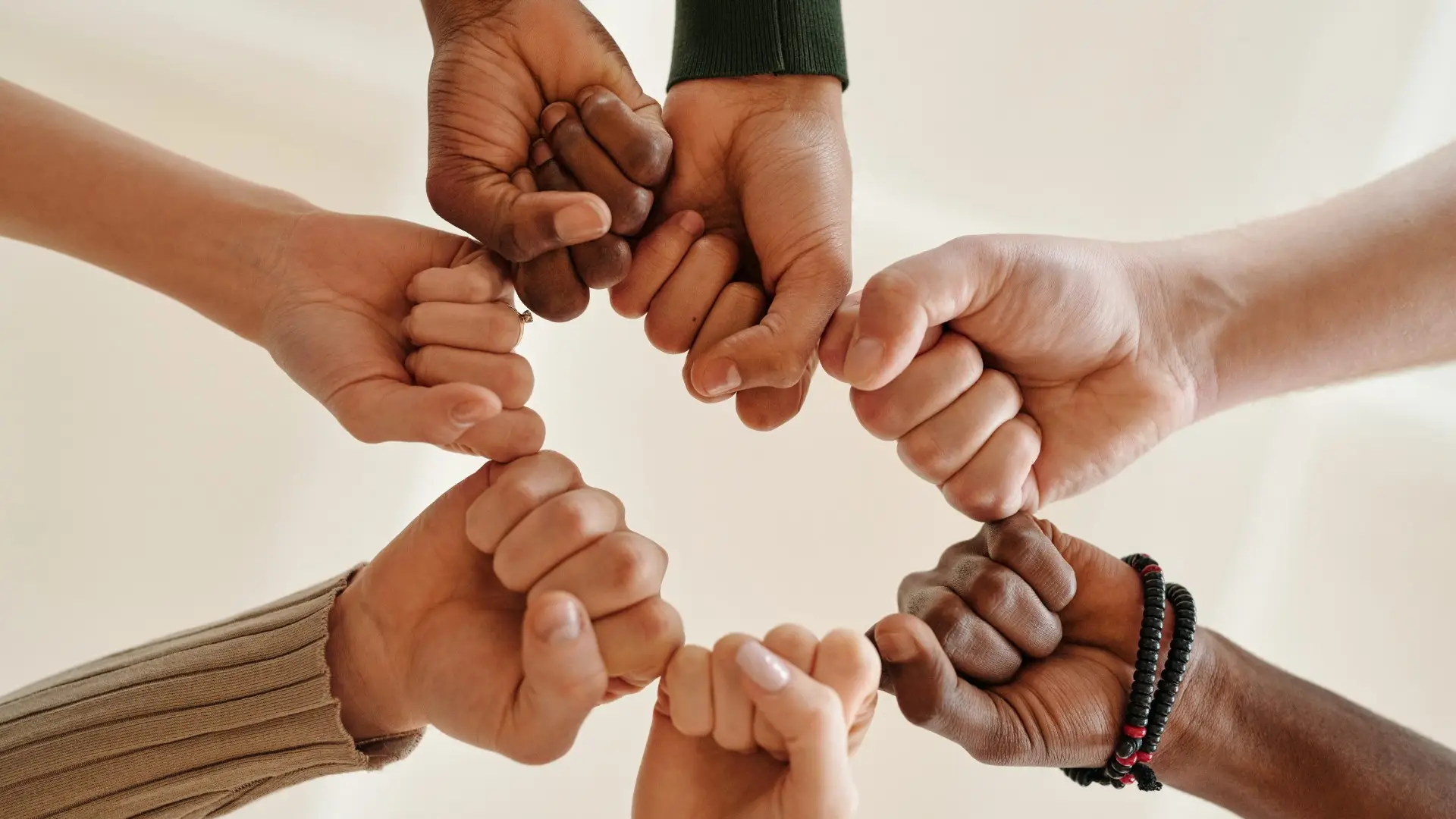 Seven hands coming together in the middle of a shot angled from below the outstretched arms