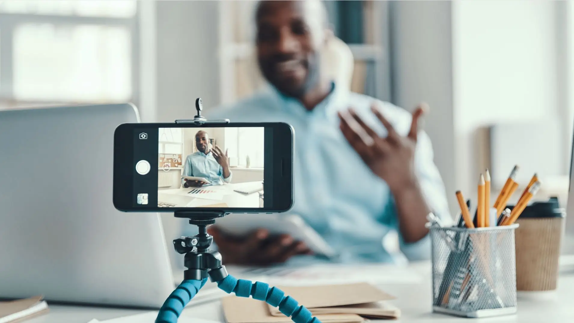 Man recording self from cell phone on a tripod sitting on his desk