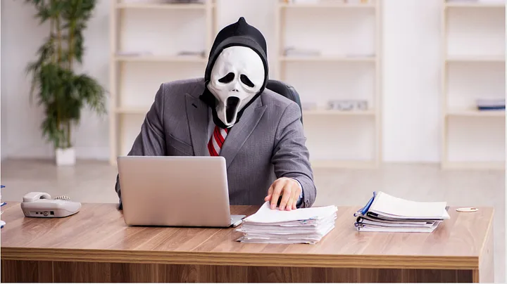 A man sitting at his desk with a Halloween mask on.