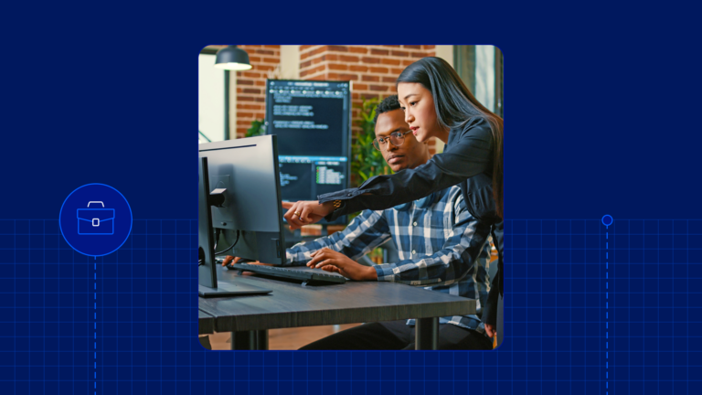 Two co-workers in front of a computer screen looking at strings of code.